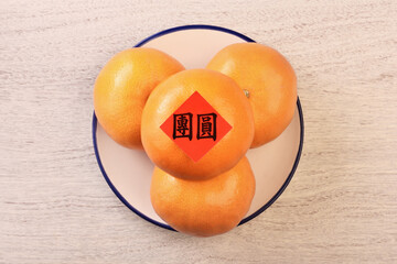 Chinese new year tangerine oranges on wooden table                         the Chinese words is 'reunion', not a logo or trademark.