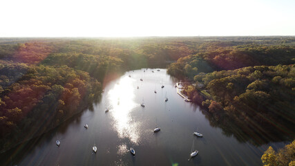 Obraz premium The sun rises over the trees and casts light onto sailboat cove below