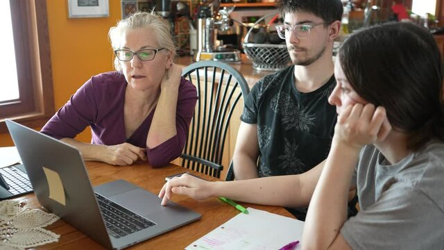 Mother and children use laptop for education, online study, home work, Boy and Girl have homework at distance learning. Lifestyle concept for family quarantine. Mother helps daughter and son.