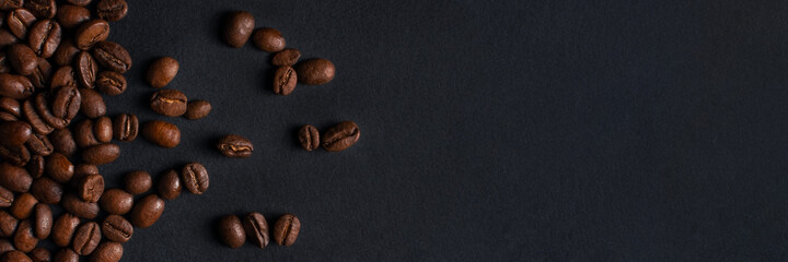 Banner with fresh roasted coffee beans closeup on black stone background. Top view, flat lay with copy space