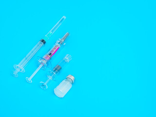 Group of syringes and vaccine on blue background. Copy space. Vaccination concept.