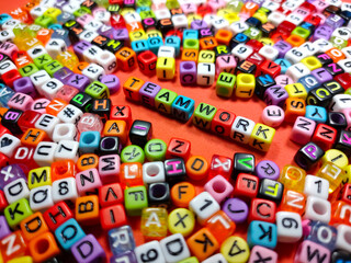 Selective focus.Colorful dice with word TEAM WORK on red background.Shot were noise and film grain.