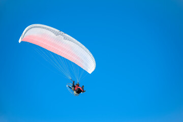 Motor paraplane flying against a rich blue sky