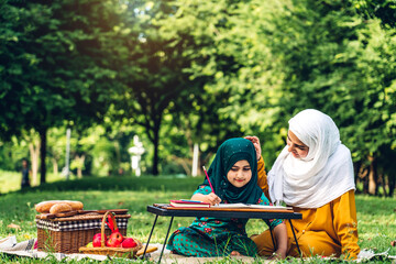 Naklejka na ściany i meble Portrait of happy religious enjoy happy love asian family arabic muslim mother and little muslim girls child with hijab dress smiling and having fun moments good time in summer park