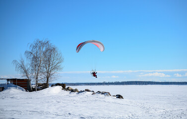 A motor paraplane flying over a frozen lake
