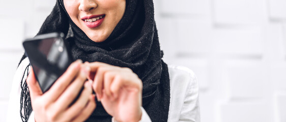 Portrait of smiling happy beautiful muslim woman relaxing using digital smartphone.Young muslim...