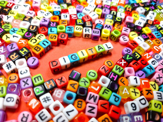 Selective focus.Colorful dice with word DIGITAL on red background.Shot were noise and film grain.