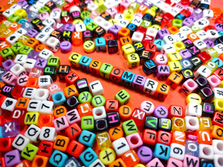 Selective focus.Colorful dice with word CUSTOMERS on red background.Shot were noise and film grain.