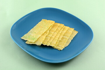 Wasabi potato chip strips on blue snack plate on light green background