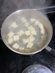 hand rolled gnocchi boiling in large pot on stove top