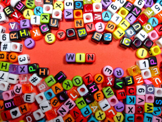 Selective focus.Colorful dice with word WIN on red background.Shot were noise and film grain.