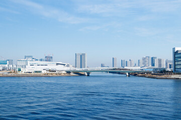 青空を背景にレインボーブリッジから見た豊洲市場と有明方面のビル群