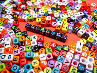 Selective focus.Colorful dice with word CURRENCY on red background.Shot were noise and film grain.