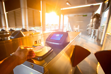 Selective focus to hand of passenger using smart card to open automatic gate machine at sky train station. Modern automatic ticket.