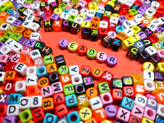 Selective focus.Colorful dice with word LEADER on red background.Shot were noise and film grain.