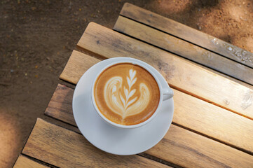 Close up hot cappuccino white coffee cup with heart shape latte art on dark brown old wood table at caff food and drink concept.