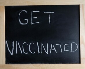 get vaccinated written on chalk board. empty vials beside sign.