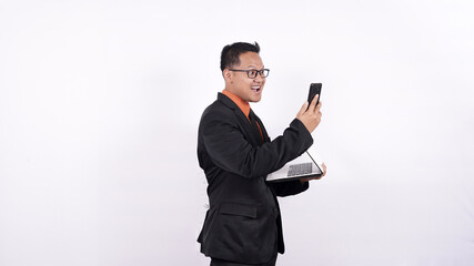 Naklejka premium businessman holds a laptop computer and looks at a cell phone isolated white background