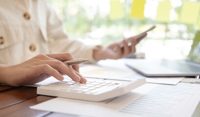 Financial businesswomen use laptop and smart phone to analyze marketing strategies and real estate data to reduce company taxes for their customers, Accounting and Tax concept.