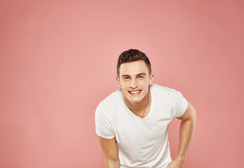 A man gestures with his hands in a white t-shirt emotions pink background
