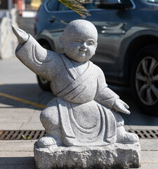 Stone figurine of little monk practicing kongfu in courtyard of Qibao Temple, a Buddhist monastery...