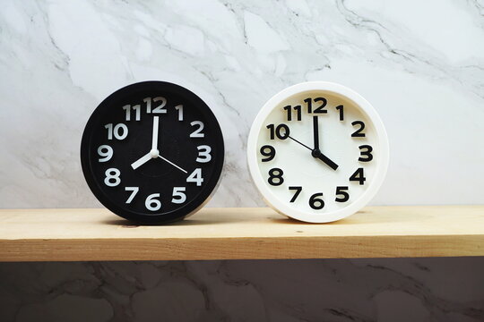 Clocks with time zone of different country on wooden shelves and marble background
