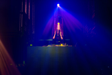 DJ on stage in disco night club mixing techno music beat . Nightlife and dance party .
