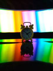 A yellow clock with colorful and black background.