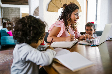 latin mother works on laptop with children playing around, Work from home. 