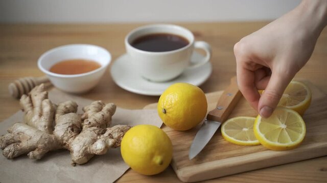 Healthy beverage kombucha. Female hands slicing fresh ginger in kitchen for fermented fresh drink