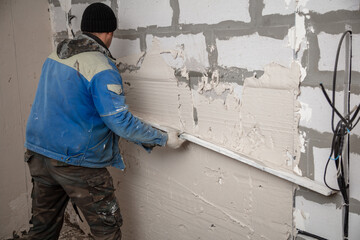 A worker plasters the walls in the room.
