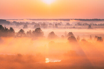 Amazing Sunrise Over Misty Landscape. Scenic View Of Foggy Morning Sky With Rising Sun Above Misty Forest And River. Early Summer Nature Of Eastern Europe. Sunset Dramatic Sunray Light Sunbeam