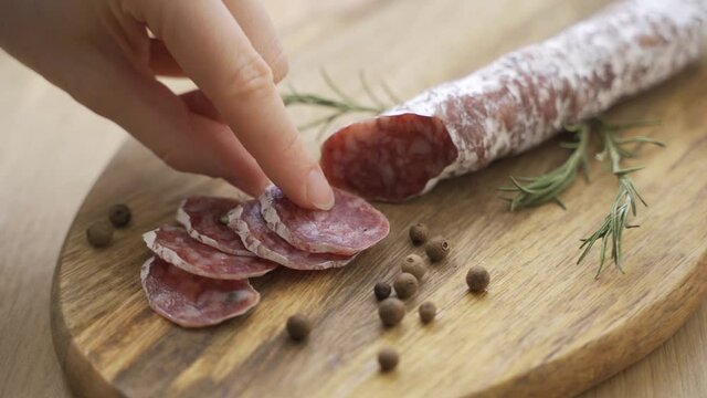 One hand takes the knife and slices of slices to savor the quality. Concept of: italy, salami and tradition.