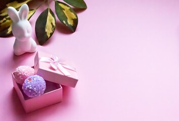 Flat lay Easter pink background with bunny and eggs in a box