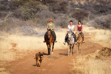 Three women ride along track with dog