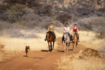 Three women ride on track with dog