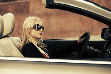 Young fashion woman in sunglasses driving convertible car