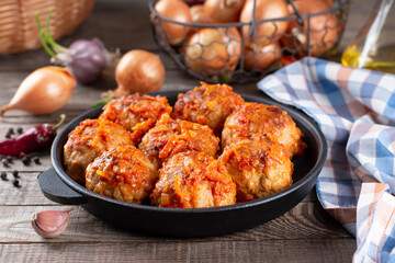 Meatballs from beef and pork with vegetables in a frying pan on a table