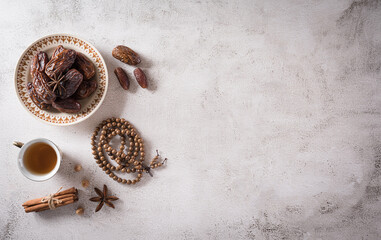 Ramadan food and drinks concept. Ramadan wood rosary, tea, and dates fruits on dark background.