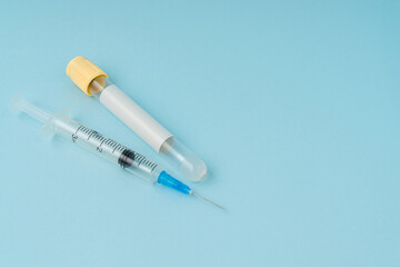 Medical syringe, face mask and blood vacuum tube on blue background with a copy space.