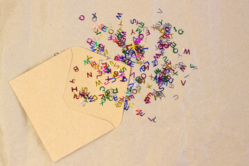 Simple kraft paper envelope with scattered bright colored small letters close up