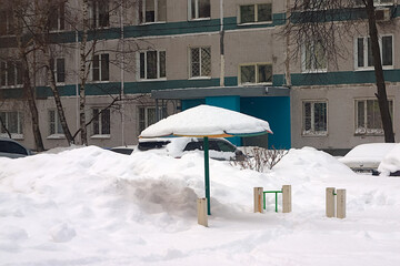 snow-covered playground near a multi-storey building