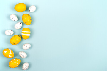 Easter eggs in yellow and white on a pastel blue background. Flat lay, top view.