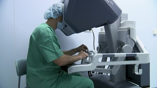 Surgeon operates with a medical robot looking inside the monitor.