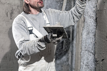 Real construction worker working on a wall inside the new house.