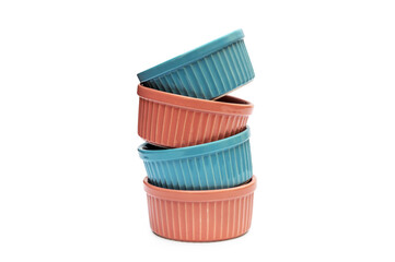 Stack of pink and blue small ceramic ramekins on white background.