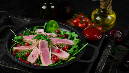 Salad: arugula, tuna and avocado on a black stone plate. Top view. Free space for text.