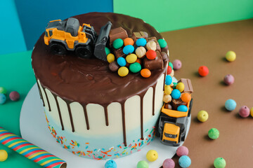 Birthday colorful cake for little boy with toy cars and colorful candies decorations. Holiday, celebration, stylish concept. Construction and transportation theme boys party.