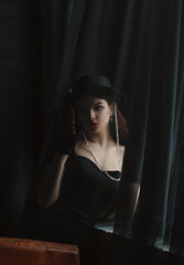 Beautiful slender long-legged brunette girl in a black dress and hat.