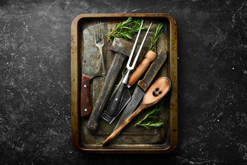 Old kitchen utensils on a metal kitchen tray on a black stone background. Retro tableware. Free...